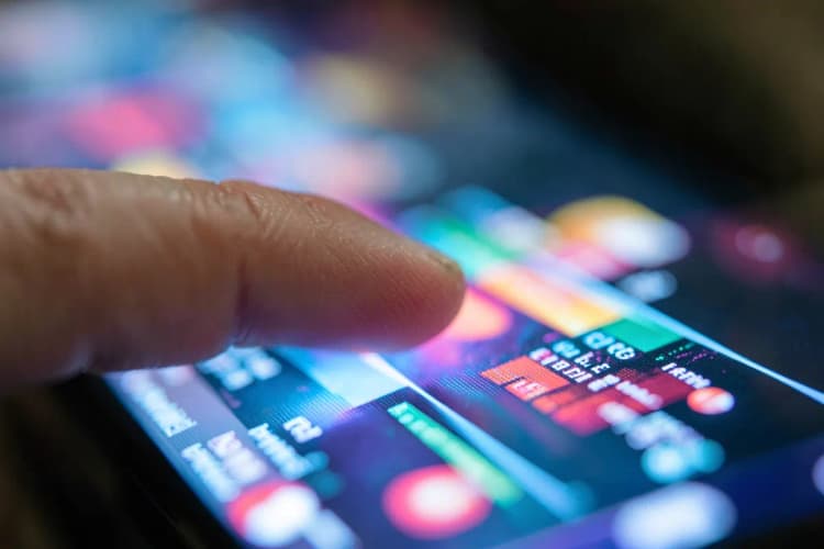 Um close-up de um dedo tocando em uma tela de TV, ativando um menu interativo com gráficos coloridos.